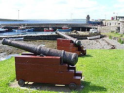 Cannon decorar el muelle de Balfour Harbour en Shapinsay, la torre redonda en el fondo es The Douche