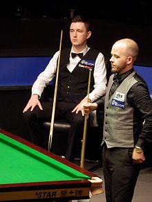 Wilson is sat with Brecel about to play a shot