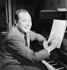 Johnny Mercer in front a piano, holding a pen.