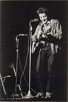 A spotlight shines on Dylan as he performs onstage.