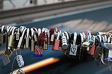 "Love locks" on the Brooklyn Bridge. Couples inscribe a date and their initials onto a lock, attach it to the bridge, and throw the key into the water as a sign of their love.