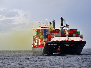 Buque de carga en el mar con vapores de color marrón provenientes de un contenedor en medio del buque