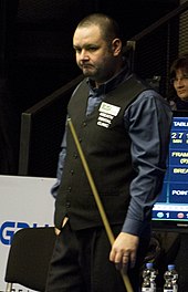 Stephen Maguire standing, holding a cue