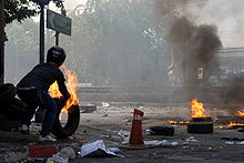 A person pushing burning tyres onto a street