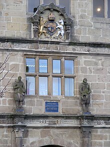 Two stone statues of Philomath and Polymaths in Elizabethan dress, on the original buildings; also featured on the contemporary school library
