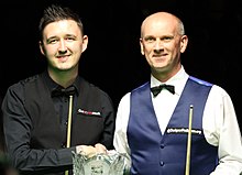 Wilson and Peter Ebdon shaking hands behind a trophy