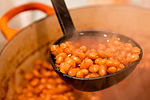 Boston baked beans being served with a ladle