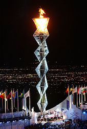 Interwoven steel frame several stories high with the lit flame at the top