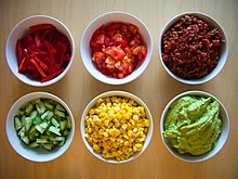 small bowls of corn, tomatoes, peppers, guacamole, and other ingredients